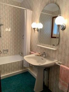 Apartamento Cambrils Centro في كامبريلس: حمام مع حوض ومرآة وحوض استحمام