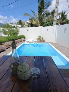 a pool with a wooden table with a bottle of wine at Bois Mapou Self Catering Apartments Unit 201 in Rivière Noire
