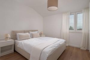Un dormitorio blanco con una cama blanca y una ventana en Spacious and fully equipped apartment near Zadar, en Smoković