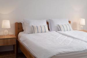 1 cama con sábanas y almohadas blancas y 2 lámparas en Spacious and fully equipped apartment near Zadar, en Smoković