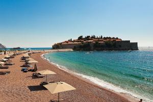 une plage avec des chaises et des parasols et l'océan dans l'établissement BMV apartment 1 with sea view, à Sveti Stefan