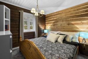 1 dormitorio con una pared de madera y 1 cama en Koselig hytte med sjel på fjellet :), en Tjørhom
