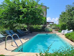 a swimming pool in a yard with chairs and a tree at Dolcedimora in Appignano