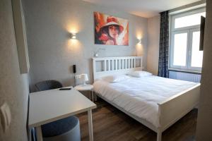 a small bedroom with a white bed and a window at Hotel Bristol in Luxembourg