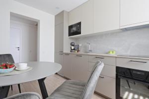 a kitchen with white cabinets and a table and chairs at Aušros apartamentai in Utena