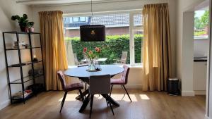 a dining room with a table and chairs and a window at Betuwe Huisje in Meteren