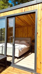 ein Bett in einer Glastür auf einer Holzterrasse in der Unterkunft Luxe Tiny House bij het Leekstermeer in Matsloot