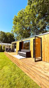 a large wooden deck with a bedroom in a tiny house at Luxe Tiny House bij het Leekstermeer in Matsloot