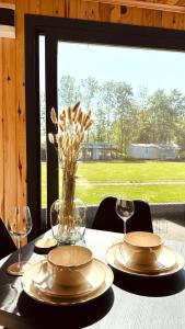 a table with plates and glasses and a vase with flowers at Luxe Tiny House bij het Leekstermeer in Matsloot