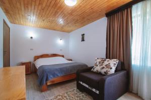 a small bedroom with a bed and a chair at Pensiunea Bradet in Malaia