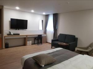 Habitación de hotel con cama y escritorio con TV. en Hotel Ciel Dongtan, en Hwaseong