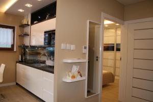 una cocina con armarios blancos y fregadero en Apartament Porta Mare 122, en Dziwnówek