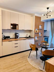 a kitchen with white cabinets and a table and chairs at DAMAR Infinity Beach and Pool Mamaia- private parking in Mamaia Sat/Năvodari