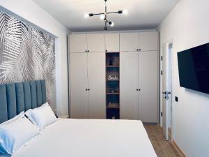 a bedroom with a white bed and a tv at DAMAR Infinity Beach and Pool Mamaia- private parking in Mamaia Sat/Năvodari +30 photos