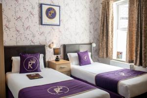 two beds in a hotel room with purple sheets at Revado Hotel in Norwich