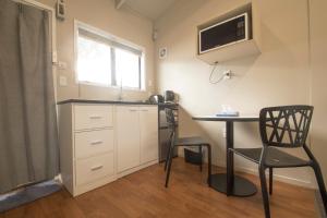 una pequeña cocina con escritorio y mesa en Middlemore Motel, en Auckland