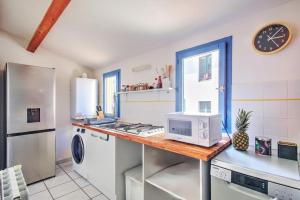 a kitchen with a counter with a microwave and a refrigerator at Uncourtsejour - Nîmes la Rome française in Nîmes
