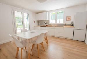 uma cozinha com uma mesa branca e cadeiras brancas em L'immeuble les 3C em Saint-Palais-sur-Mer