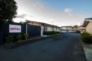 an empty street with a motel sign on a fence at Middlemore Motel in Auckland