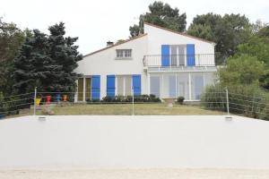une maison blanche avec des portes bleues et une clôture dans l'établissement L'immeuble les 3C, à Saint-Palais-sur-Mer