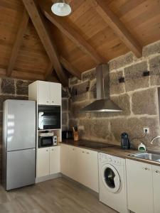 a kitchen with white appliances and a stone wall at As Fontaiñas 