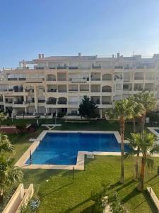 a large apartment building with a swimming pool and palm trees at Vereda Golf - Apartamento in Roquetas de Mar