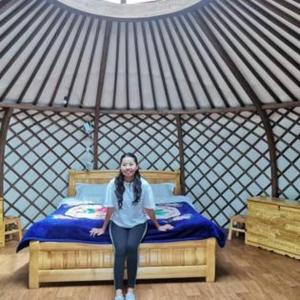 Una donna in piedi accanto a un letto in una yurta di Talbiun Lodge a Hujirt