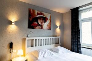 Un dormitorio con una cama blanca con un cuadro en la pared. en Hotel Bristol, en Luxemburgo