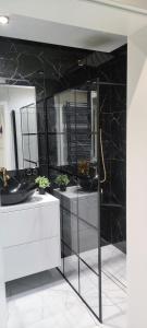 een badkamer met zwarte marmeren muren en een spiegel bij Apartament Royal in Rzeszów