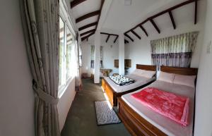 um pequeno quarto com duas camas e uma janela em Acme Divine View em Nuwara Eliya