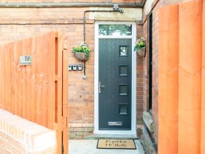 a black door on a brick house with two potted plants at Mansfield Town Centre Flats in Mansfield