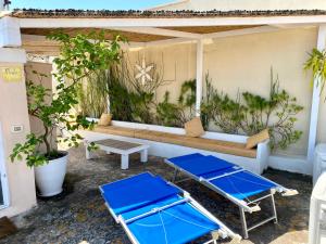 two blue lounge chairs and a bench on a patio at Casa Mida - Guest House in Pezze di Greco