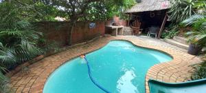 a swimming pool in a backyard with a brick floor and a fence at Eagle Forest inn in Durban