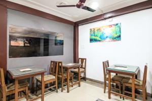 City Star Hotel & Restaurant في Jawāharnagar: غرفة طعام مع طاولات وكراسي ولوحة