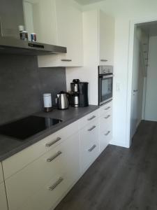 a kitchen with white cabinets and a black counter top at Apart Schleswig in Schleswig