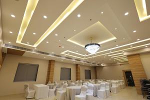 un salón de banquetes con mesas y sillas blancas y una lámpara de araña en Hotel Sharda Residency en Patna
