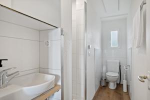 a white bathroom with a sink and a toilet at Erlen Rooms in Lucerne