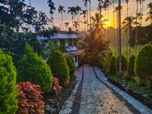 a cobblestone road in front of a house with palm trees at CentreHome Villa Wayanad in Meenangadi