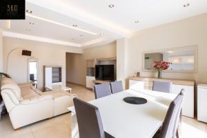 Beautiful, spacious 3BR home with private Balcony with 360 Estates في سانت جوليانز: غرفة طعام وغرفة معيشة مع طاولة وكراسي بيضاء