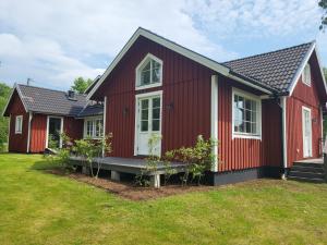 a red house with a bench in a yard at The Wine Lodge-Bo på vingård in Vittsjö