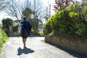 a man walking down a path carrying a surfboard at Gwithian Holidays in Hayle