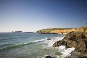 a beach with rocks and the ocean on a sunny day at Gwithian Holidays in Hayle