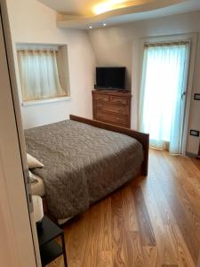 a bedroom with a bed and a dresser and a television at Savoia Terrace with Mountain View in Taceno