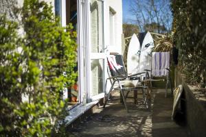 a porch with chairs and surfboards on a house at Gwithian Holidays in Hayle