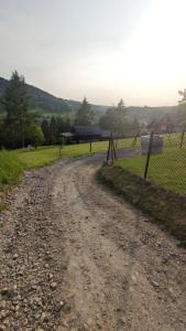 a dirt road with a fence next to a field at Domek na górce 2 in Krościenko