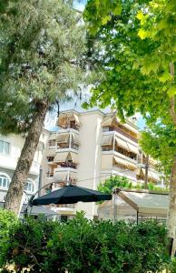 un bâtiment avec un parasol et des arbres devant lui dans l'établissement Studio near University of Thessaly, à Larissa