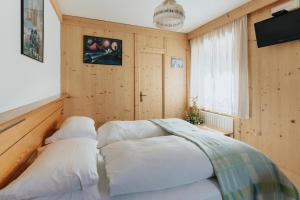 a bedroom with wooden walls and a bed with white pillows at Locanda Montana in San Vito di Cadore