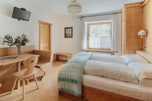 a bedroom with a bed and a desk and a window at Locanda Montana in San Vito di Cadore