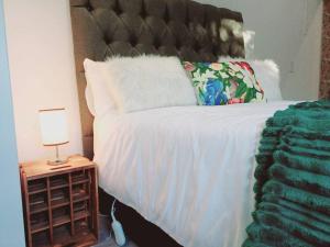 Una cama con una manta blanca y una lámpara en una mesita de noche en Charm Nest - Uncapped Wi-fi & Self Check-in, en Ciudad del Cabo