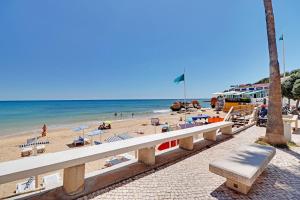 a beach with chairs and people on the sand and the ocean at Albufeira Valley 2 With Pool by Homing in Albufeira
